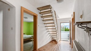 A narrow hallway with a wooden staircase, a radiator, and a bed in a room with green walls. - Holiday Home 'Haus Steinheim' with Shared Terrace, Garden, and Wi-Fi (Dillingen an der Donau)