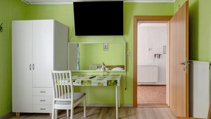 A room with a bed, a desk with a chair, a wardrobe, a television, and a door leading to another room. - Holiday Home 'Haus Steinheim' with Shared Terrace, Garden, and Wi-Fi (Dillingen an der Donau)