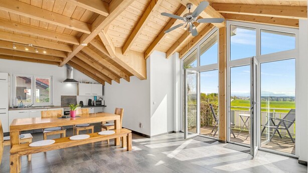 A modern kitchen with wooden beams, a dining area with a large table and benches, and a balcony with a view. - Holiday Apartment 'Cosy Home Allgäu' with Mountain View, Balcony and Wi-Fi (Haldenwang)