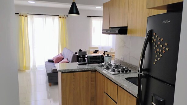Una cocina moderna con armarios de madera, un refrigerador negro, una estufa a gas y una cafetera.