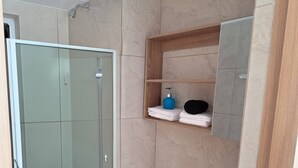 Un baño moderno con cabina de ducha de vidrio, inodoro blanco y tocador de madera con espejo.