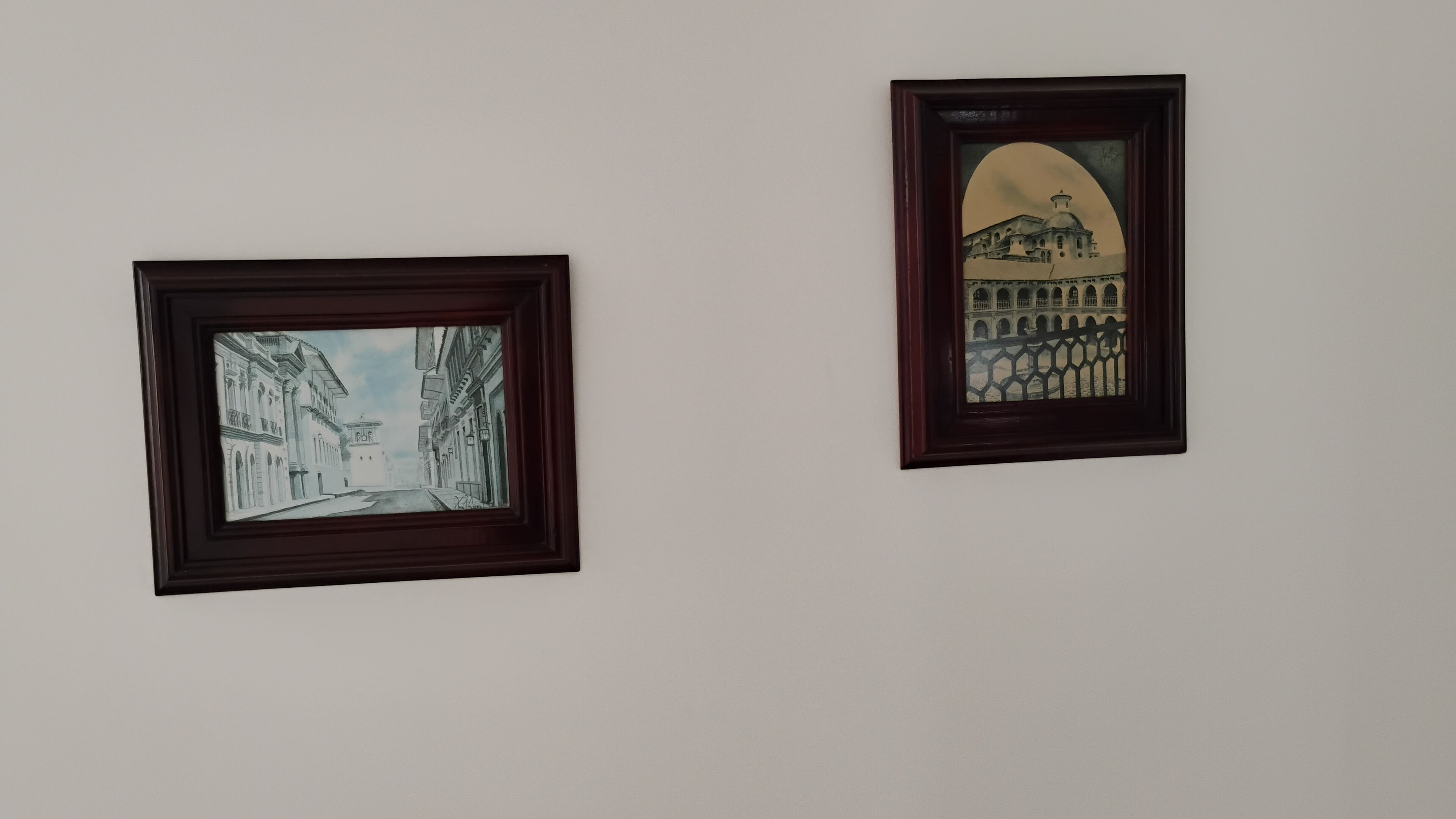 Two framed artworks on a plain wall.