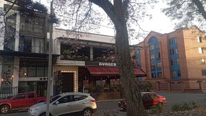Un restaurante con toldo rojo y mesas al aire libre.