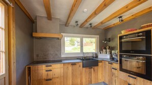Une cuisine moderne avec des meubles en bois, un plan de travail noir, un évier à deux bacs et un four encastré.
