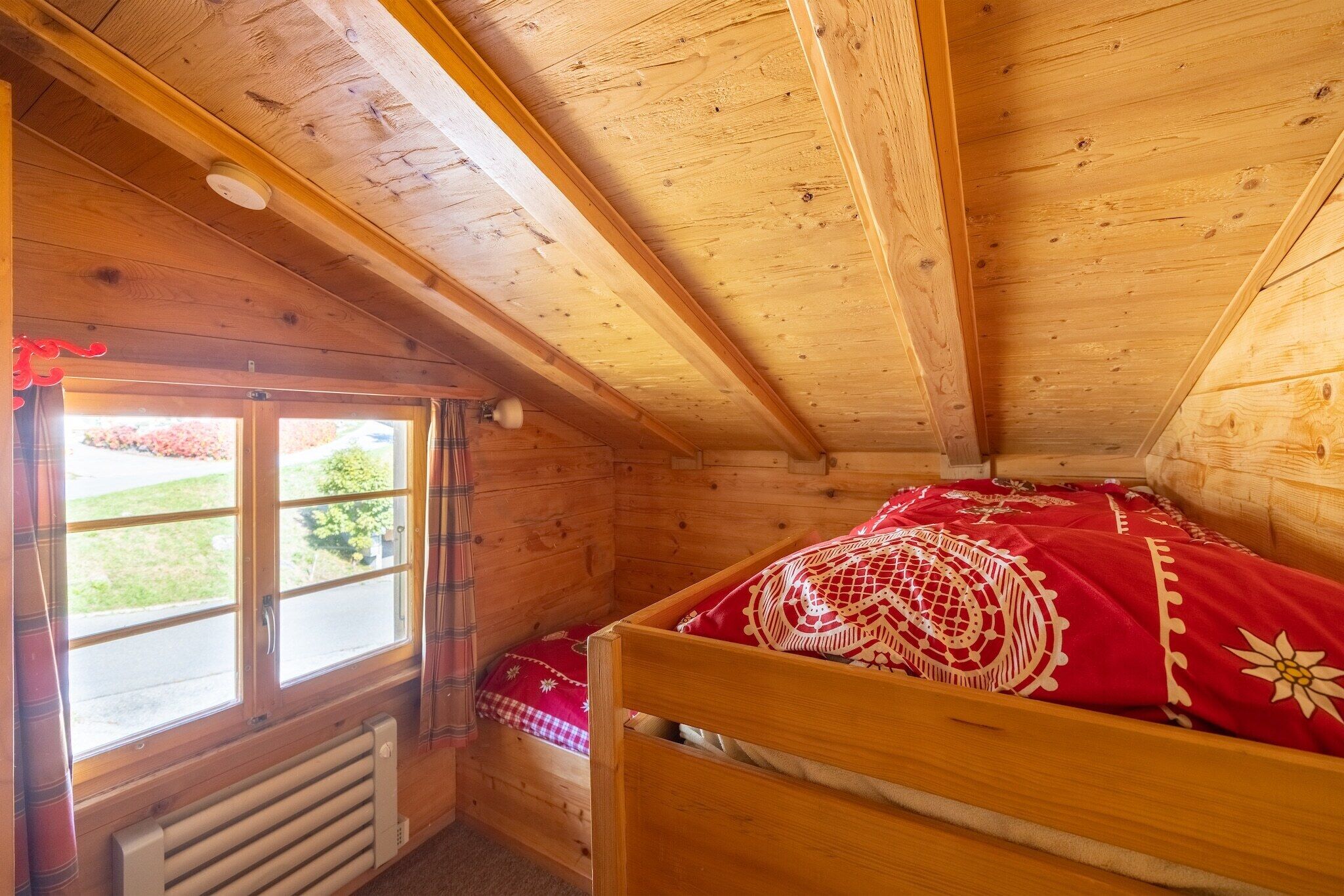 A wooden cabin room with a bed, a window, and a radiator.