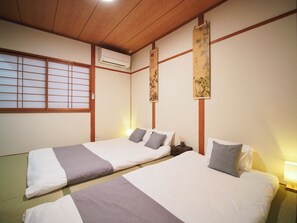 Ein traditioneller japanischer Raum mit zwei Betten, Holzbalken, Tatami-Böden und Shoji-Schiebetüren.