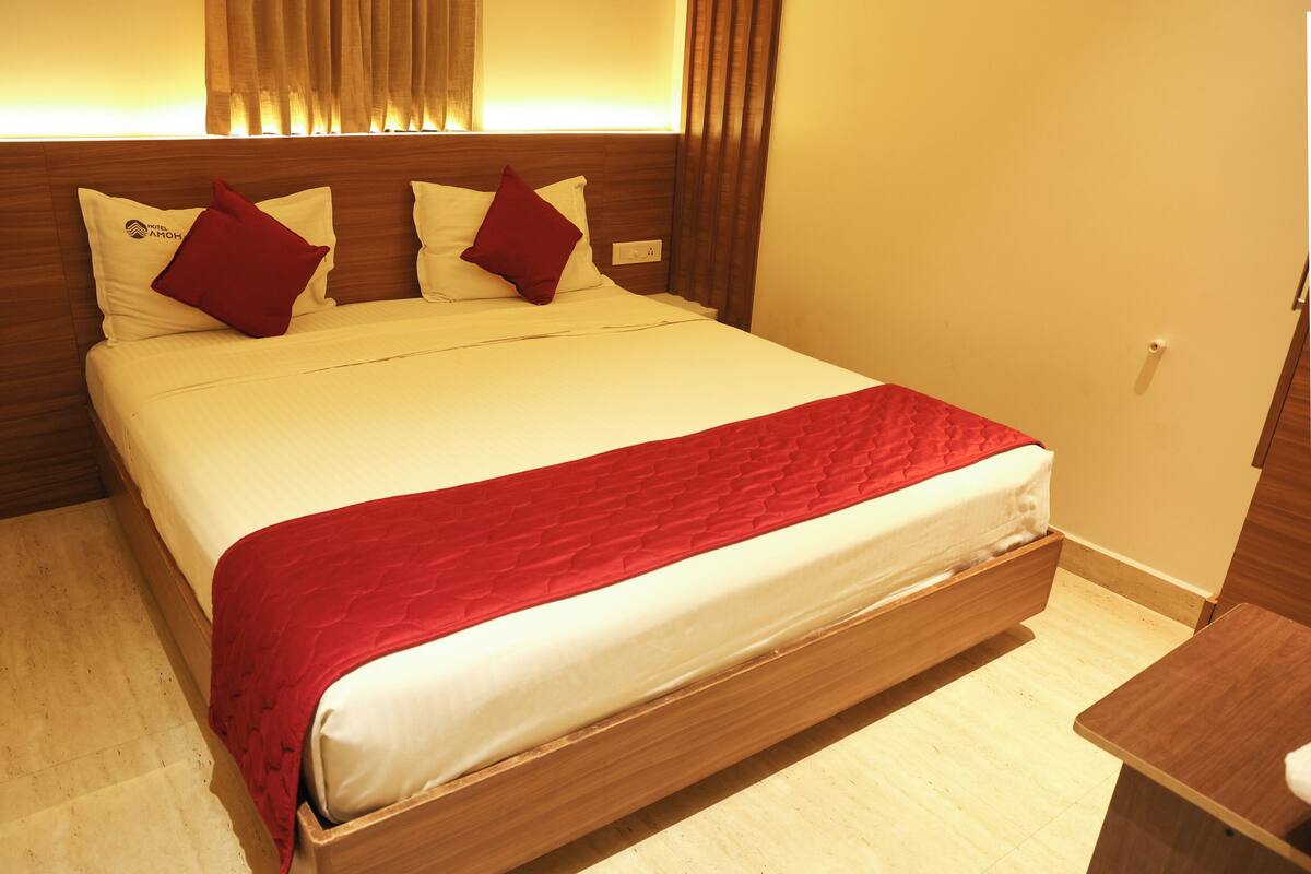 Une chambre d’hôtel avec un grand lit, une tête de lit en bois et un coussin décoratif rouge.