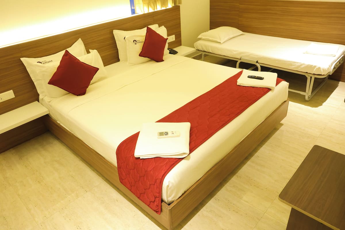 Une chambre d’hôtel avec un grand lit, un lit plus petit et un bureau.