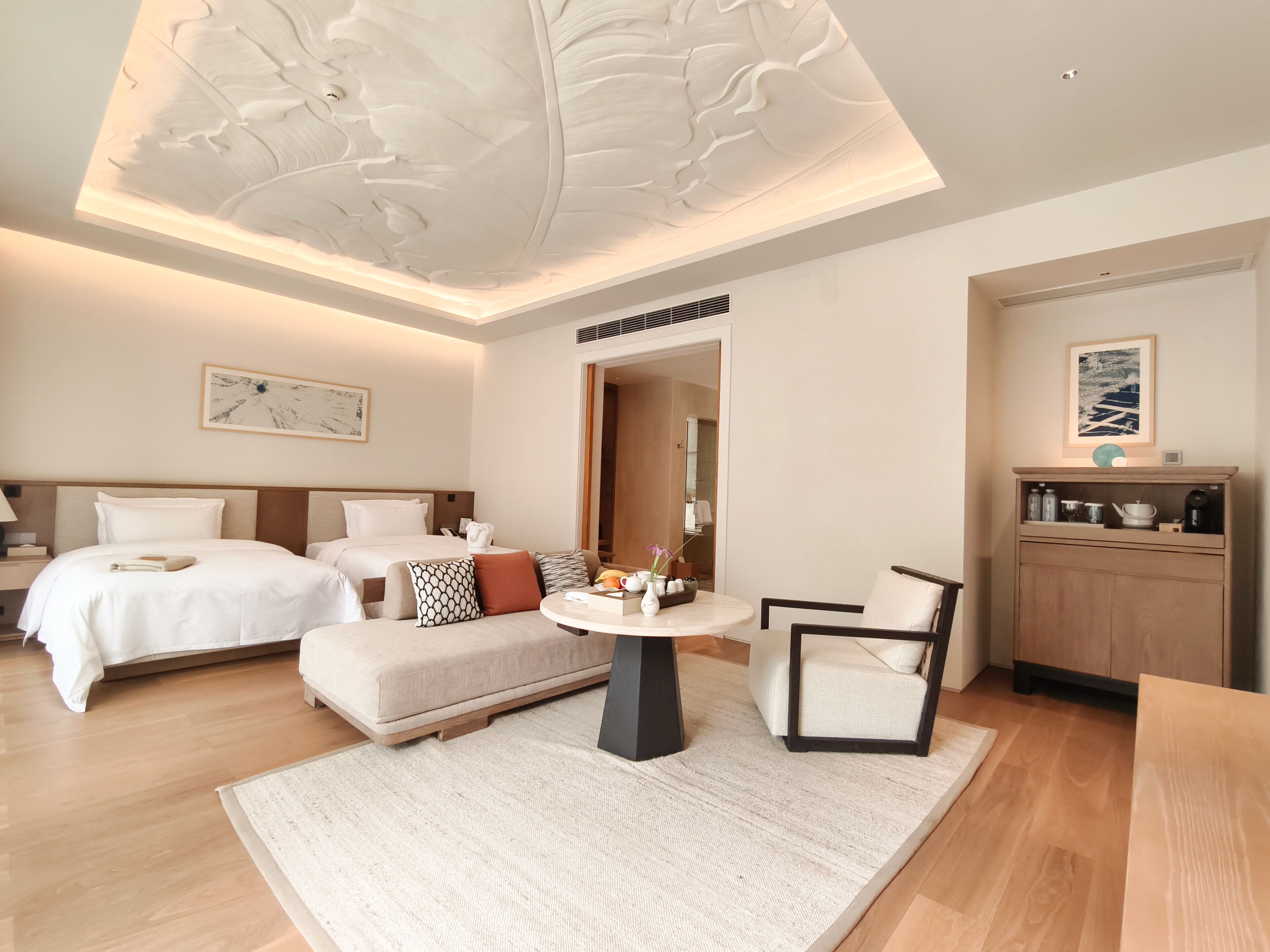 Una habitación de hotel moderna con una cama grande, un sofá, una mesa redonda y una kitchenette.