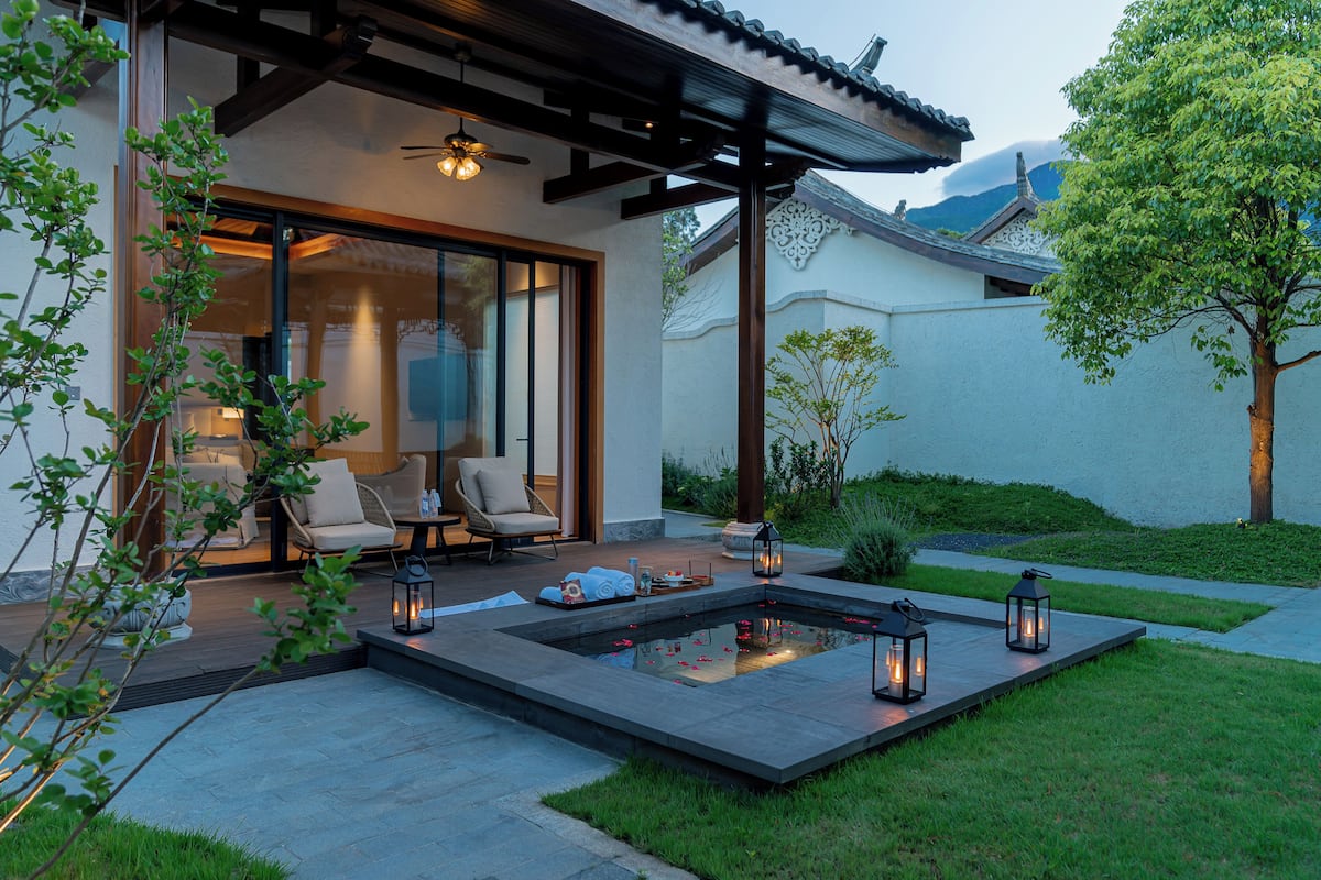 A traditional Japanese-style house with a koi pond, outdoor seating, and lanterns.