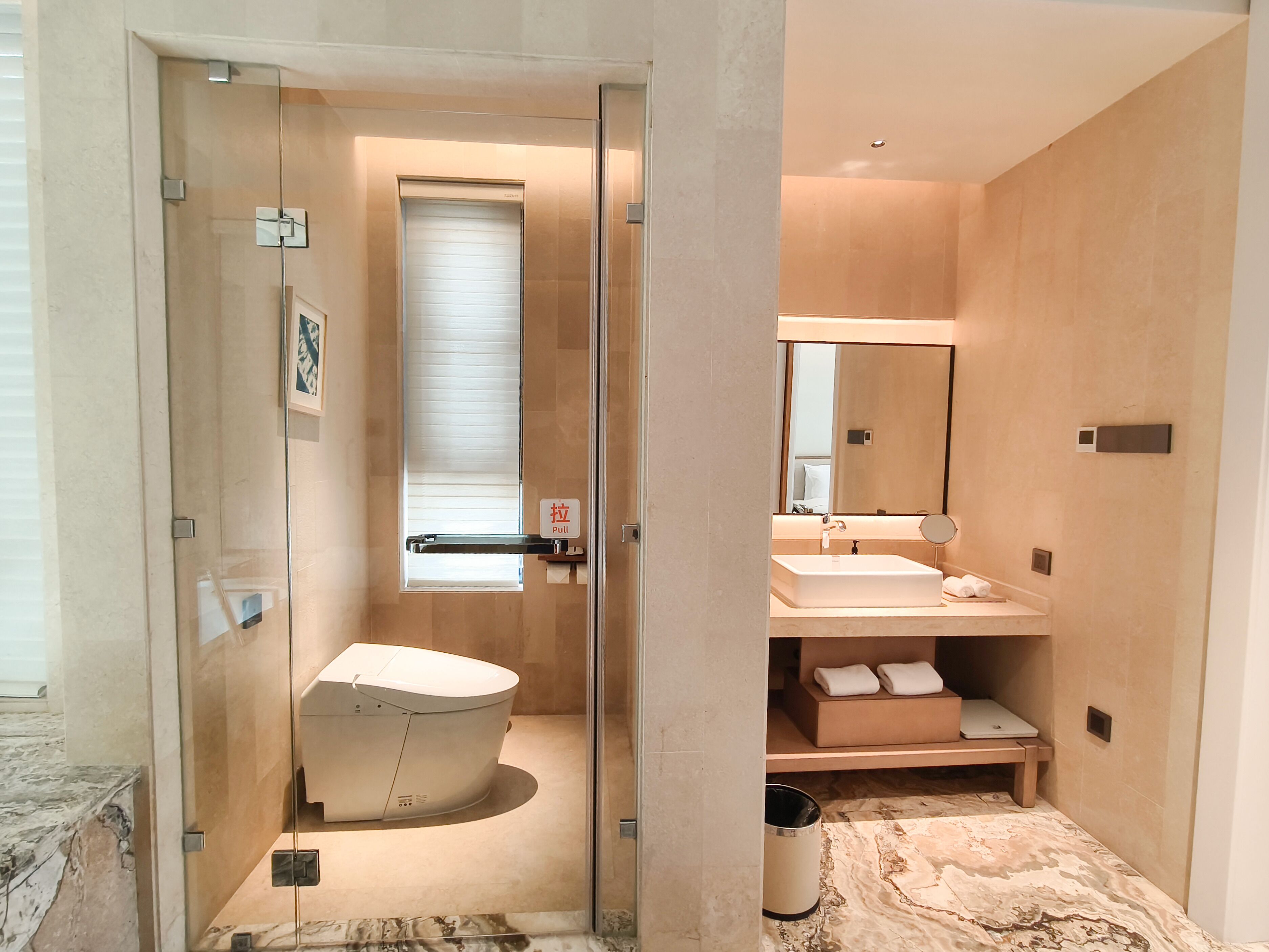 A modern bathroom with a glass shower enclosure, a toilet, a sink, and a mirror.