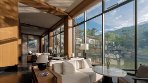 A modern hotel lobby with a sofa, chairs, and a table. Large windows offer a view of a mountainous landscape. - Dali Taoxi Secret Manor (Dali)