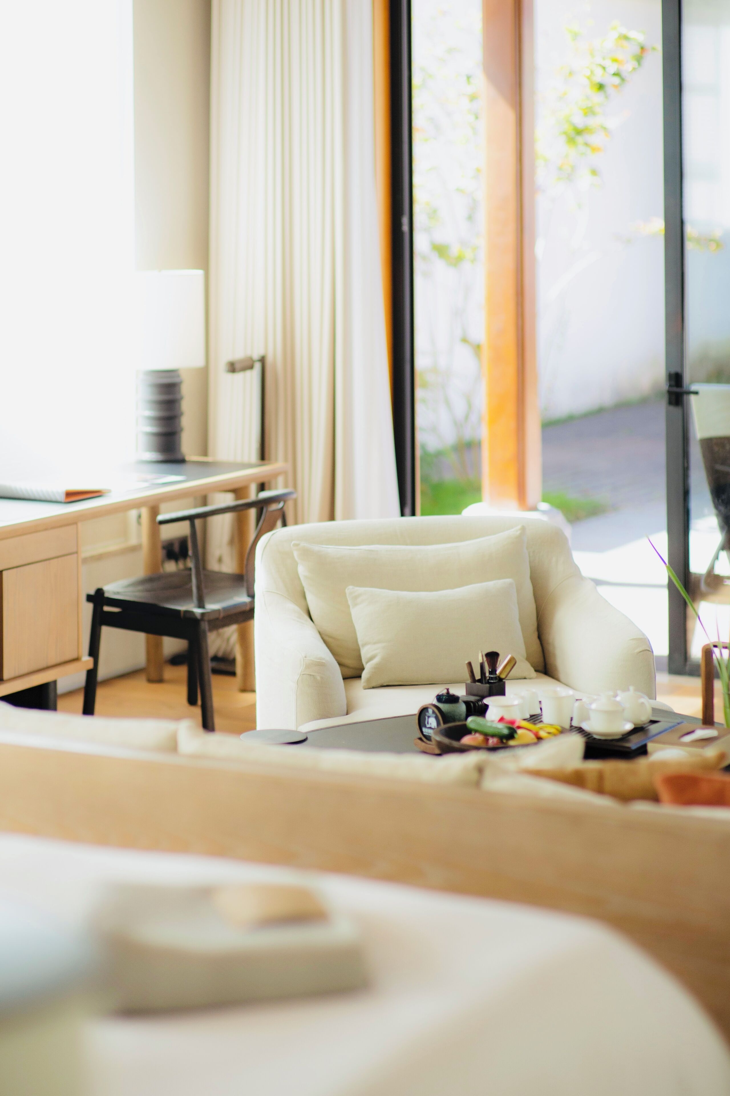 A modern hotel room with a sofa, a desk, and a dining area with a teapot set.