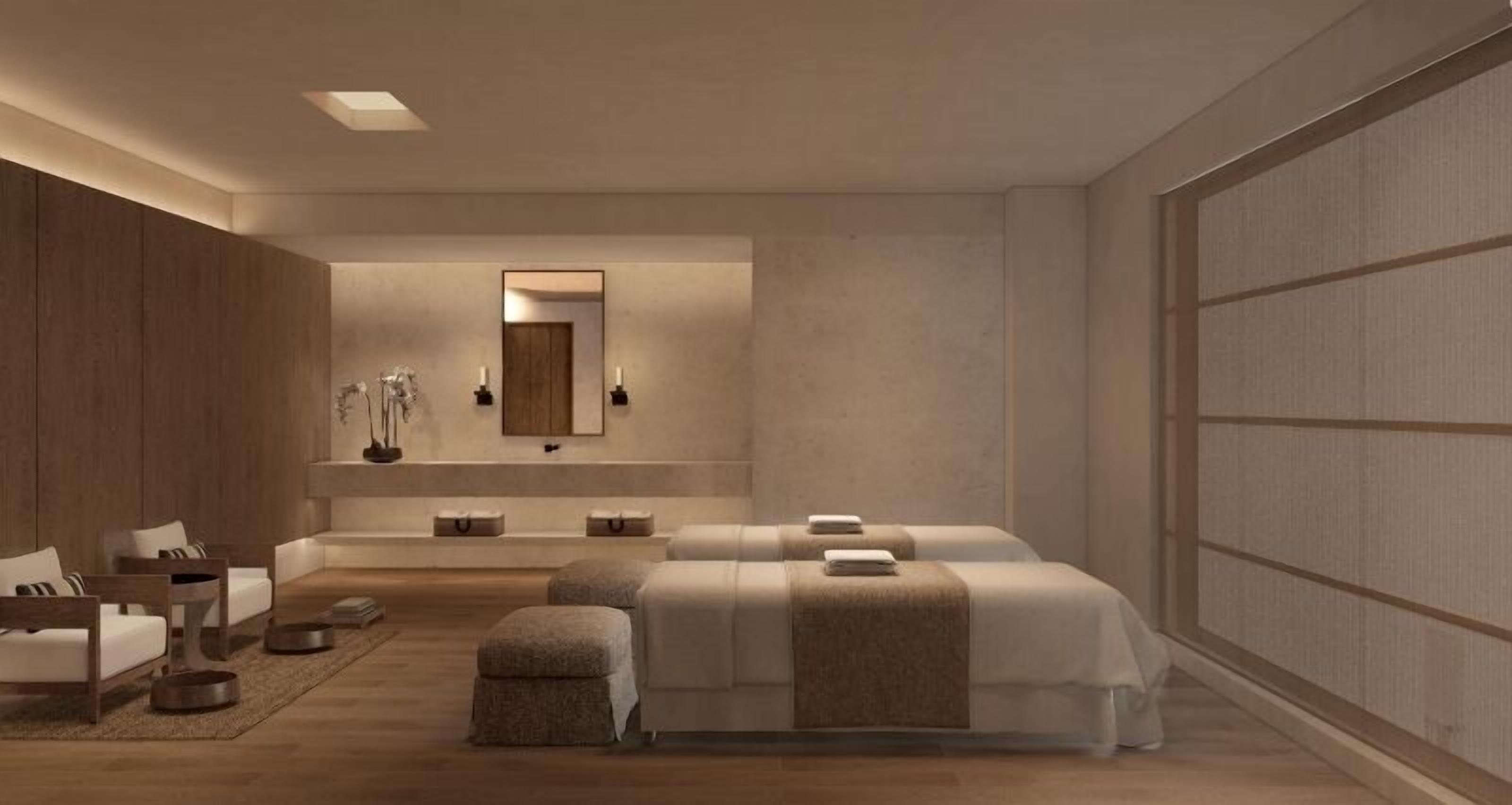 A modern bedroom with a large bed, two bedside tables, a mirror, and a seating area with a sofa and chairs.