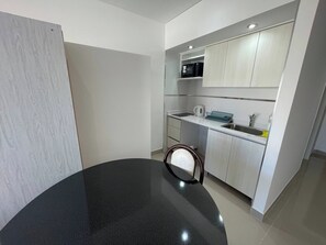 Cocina moderna con armarios blancos, encimera negra y microondas.