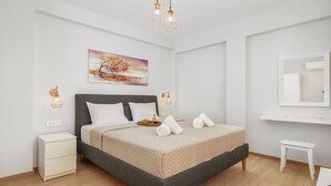 A modern bedroom with a bed, bedside tables, a small bench, and a painting on the wall. - Achilleas 2-bedroom apartment (Athina)