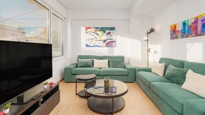 A modern living room with a green sofa, a flat-screen TV, a coffee table, and artwork on the walls. - Achilleas 2-bedroom apartment (Athina)