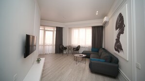 Ein modernes Wohnzimmer mit Flachbildfernseher, einer Couch, einem Couchtisch und einem Essbereich mit Stühlen und einem Tisch.
