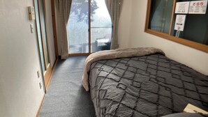 Een slaapkamer met een bed, een schuifdeur naar een balkon en een raam met uitzicht.