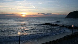 Un coucher de soleil sur l’océan, avec des vagues qui s’écrasent sur une côte rocheuse.