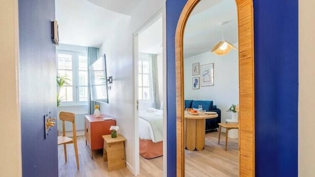Habitació d'hotel moderna amb terra de fusta, un llit, escriptori, cadira, taula petita i taula rodona amb cadires.