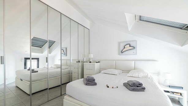 Un dormitorio moderno con una cama grande, vestidor y tragaluz.