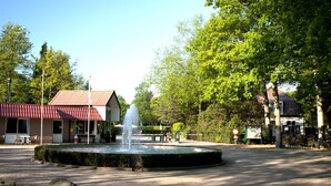 A public square with a fountain, paved walkway, and buildings with red roofs. - Beautiful Cottage Near Giethoorn (De Bult)