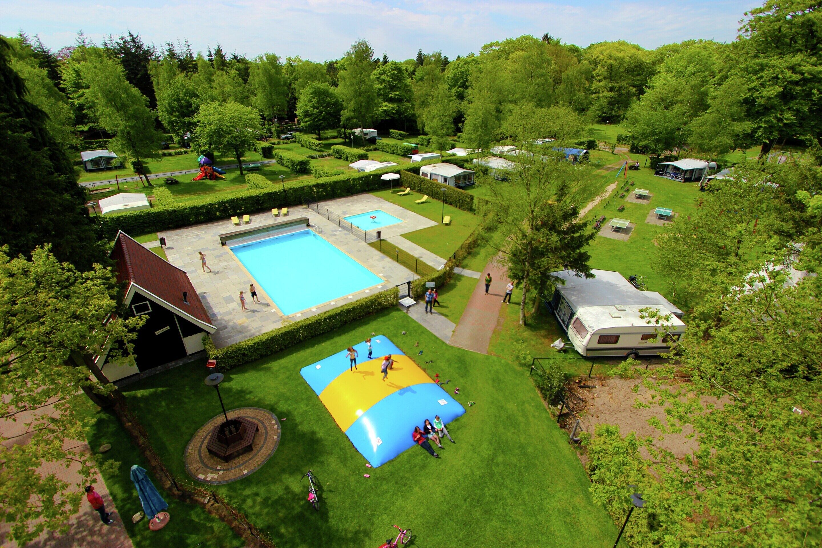 A campsite with a swimming pool, a children's play area, and RVs.