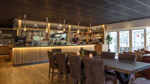 A modern bar area with a wooden counter, bar stools, and hanging pendant lights. - Beautiful Cottage Near Giethoorn (De Bult)