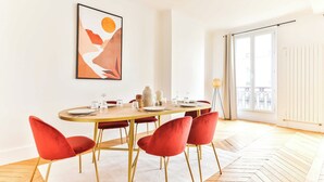 A dining area with a round table, red chairs, and a white rug.