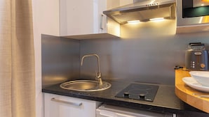 A modern kitchen with a stainless steel sink, a built-in stovetop, and a microwave. - Lovely studio for 2 people - Sentier (Paris)