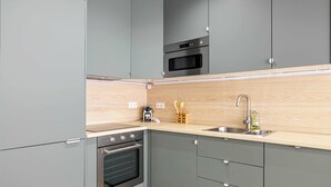 A modern kitchen with grey cabinets, a wooden countertop, stainless steel appliances, and a sink.