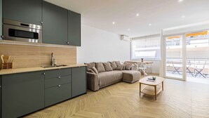 A modern kitchen with grey cabinets, a built-in oven, and a herringbone-patterned floor.