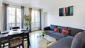 A modern living room with a sofa, a glass coffee table, and a dining area with a table set for two.