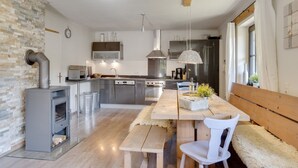 A modern kitchen with a central island, stainless steel appliances, and a rustic stone wall. - Chalet Leogang near Skilift & Bikepark (Leogang)