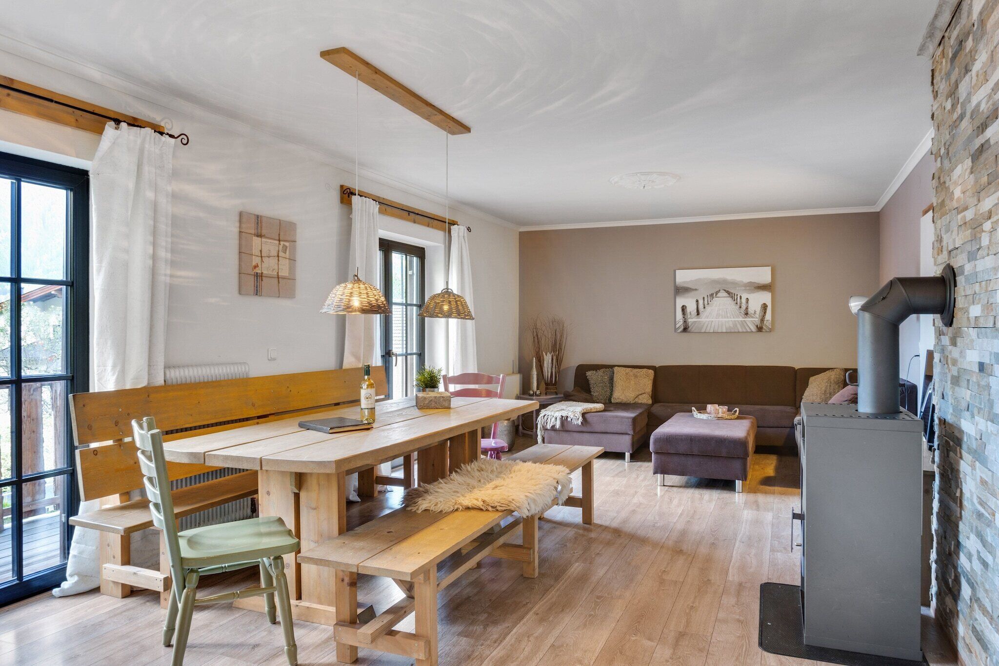 Una sala de estar acogedora con una mesa de madera, bancos y un sofá. Se observa una chimenea a la derecha.