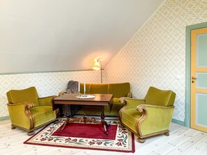 Een kamer met een hoekbank, twee fauteuils, een bijzettafeltje en een lamp.