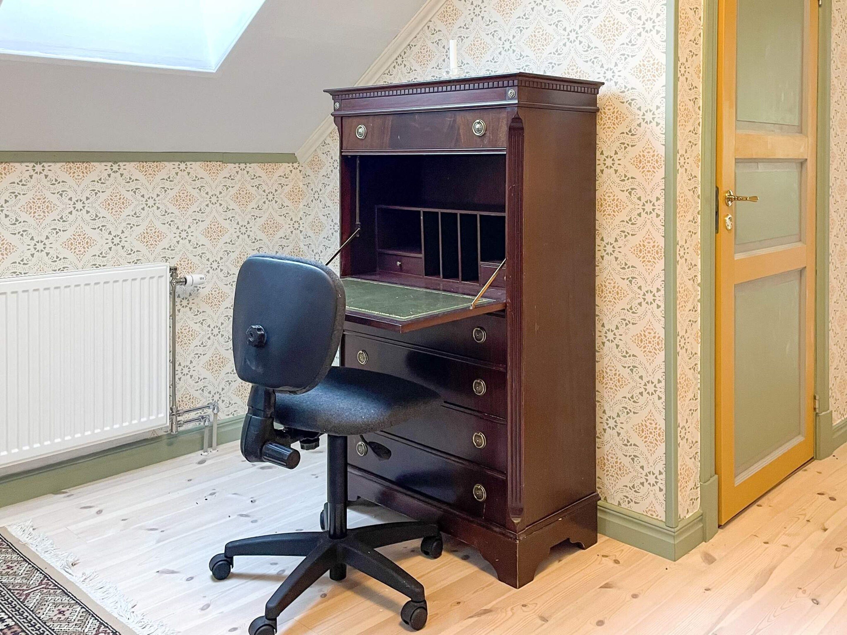 A room with a desk, chair, and a door.