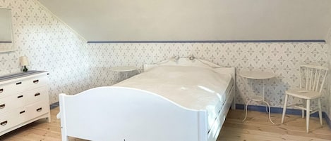 Un dormitorio con una cama individual, un aparador, una silla y una mesita.