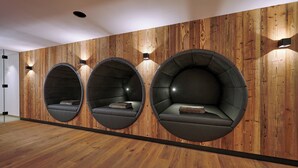 A modern interior with three circular seating pods against a wooden wall, each with a cushion and a small table. - Vacation apartment Hochfelln, 1-6pers., 2 sep. 1st bedroom, 1st floor, east-facing balcony with lake & distant view (Chieming)