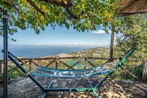 Un hamac sous une pergola, avec vue sur la mer et une ville côtière.
