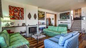 A living room with green and blue patterned sofas, a fireplace, and various artworks on the walls. - Stunning private villa with private pool, WIFI, A/C, TV, patio and panoramic view, close to Sorr... (Massa Lubrense)