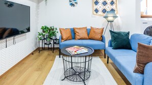Un salon moderne avec un canapé bleu, une table basse, un téléviseur et un climatiseur fixé au plafond.