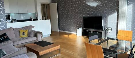 A modern living room with a sofa, coffee table, and dining area.