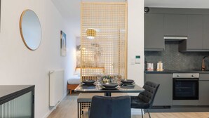 Una cocina moderna con armarios grises, horno empotrado y comedor con mesa dispuesta para cuatro.