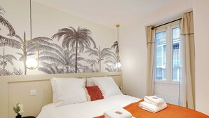 A hotel room with a bed, a nightstand, a wall mural, and a window with curtains. - Magnificent Apartment 1BR/4P - Arc de Triomphe (Neuilly-sur-Seine)