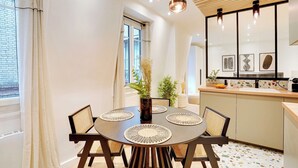 A modern kitchen with a round dining table, pendant lights, and a view of the cityscape. - Magnificent Apartment 1BR/4P - Arc de Triomphe (Neuilly-sur-Seine)