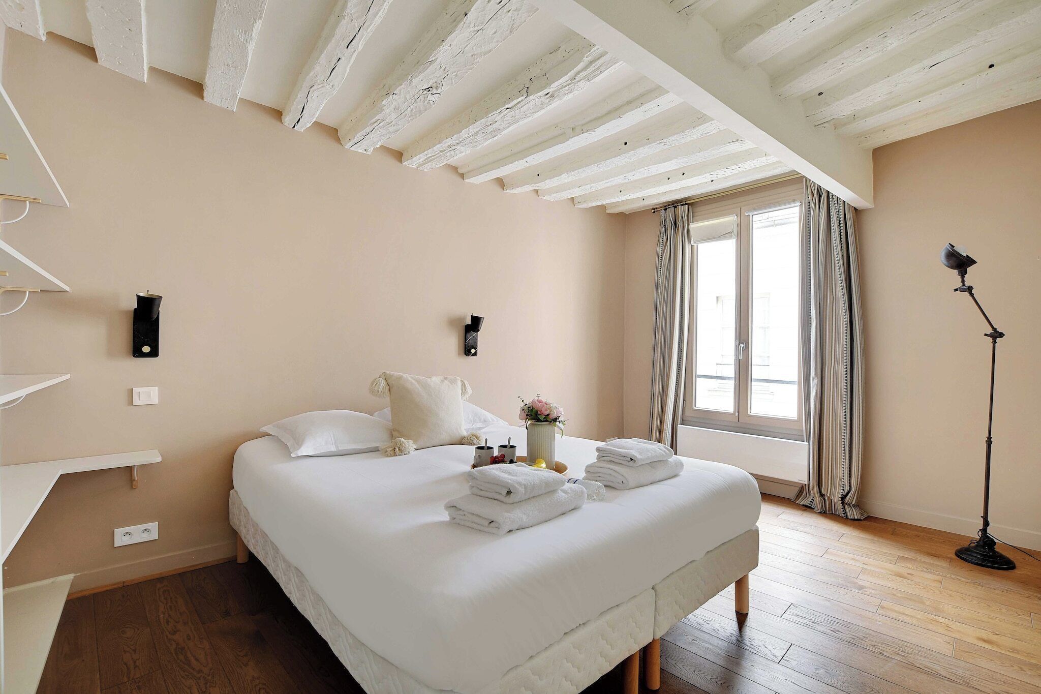Une chambre à coucher avec un lit, des tables de chevet, une commode, une lampe et une fenêtre avec des rideaux.
