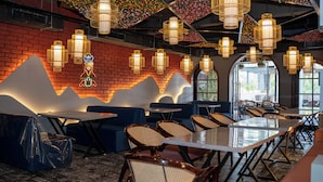 A restaurant with a brick wall, wooden tables, blue cushioned seating, and hanging lantern-style lights. - Hotel W Grand - A Boutique Hotel (Haridwar)