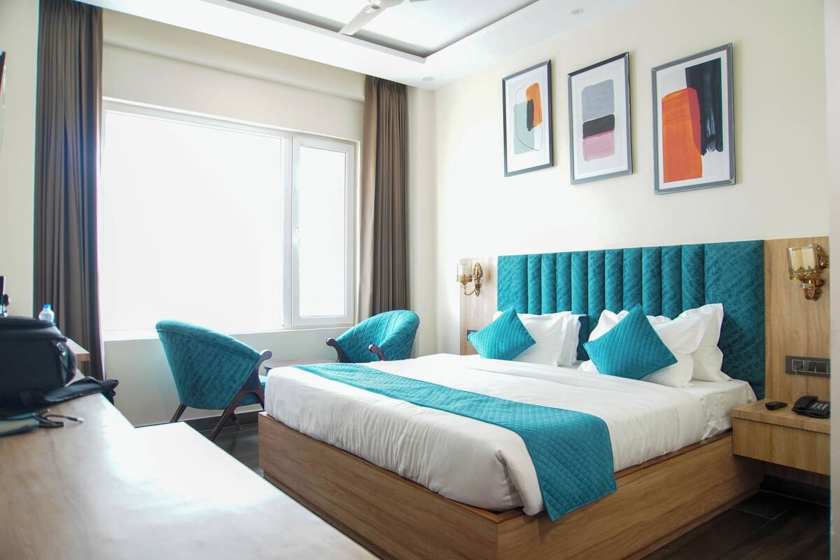 Ein Hotelzimmer mit einem großen Bett, zwei Stühlen, einem Schreibtisch und einem Fenster.